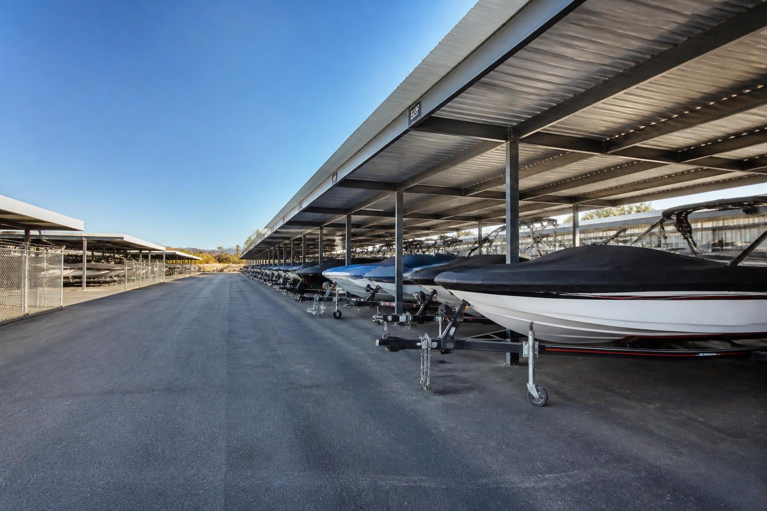 Covered boat and watercraft storage with rows of boats on trailers under metal canopies